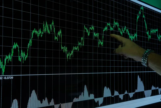 A hand points to a financial graph on a digital screen, indicating market trends. Comprendre les indicateurs conjoncturels suisses