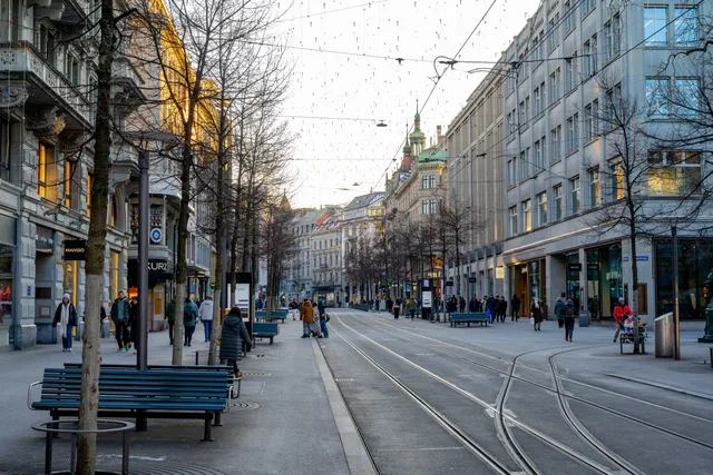 A lively street view of Bahnhofstrasse in Zurich, Switzerland, featuring pedestrians and iconic architecture. Estimer la taille d'un marché suisse avec des sources publiques